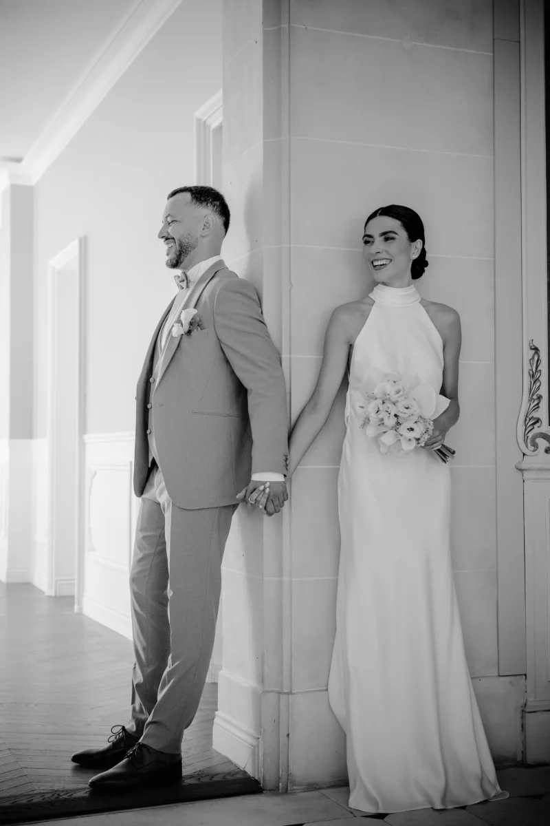 First touch en noir et blanc : les mariés se tiennent la main de part et d'autre d'un pilier, sans se voir