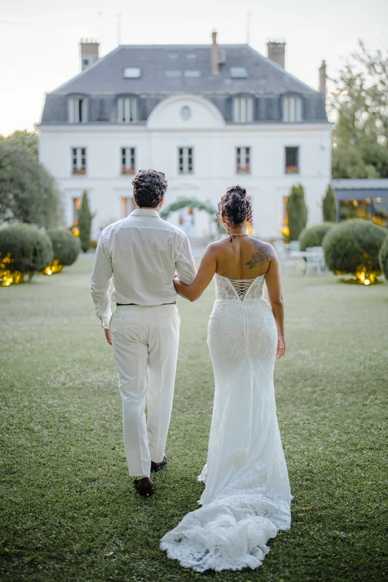 Les mariés marchent bras dessus bras dessous vers le château illuminé